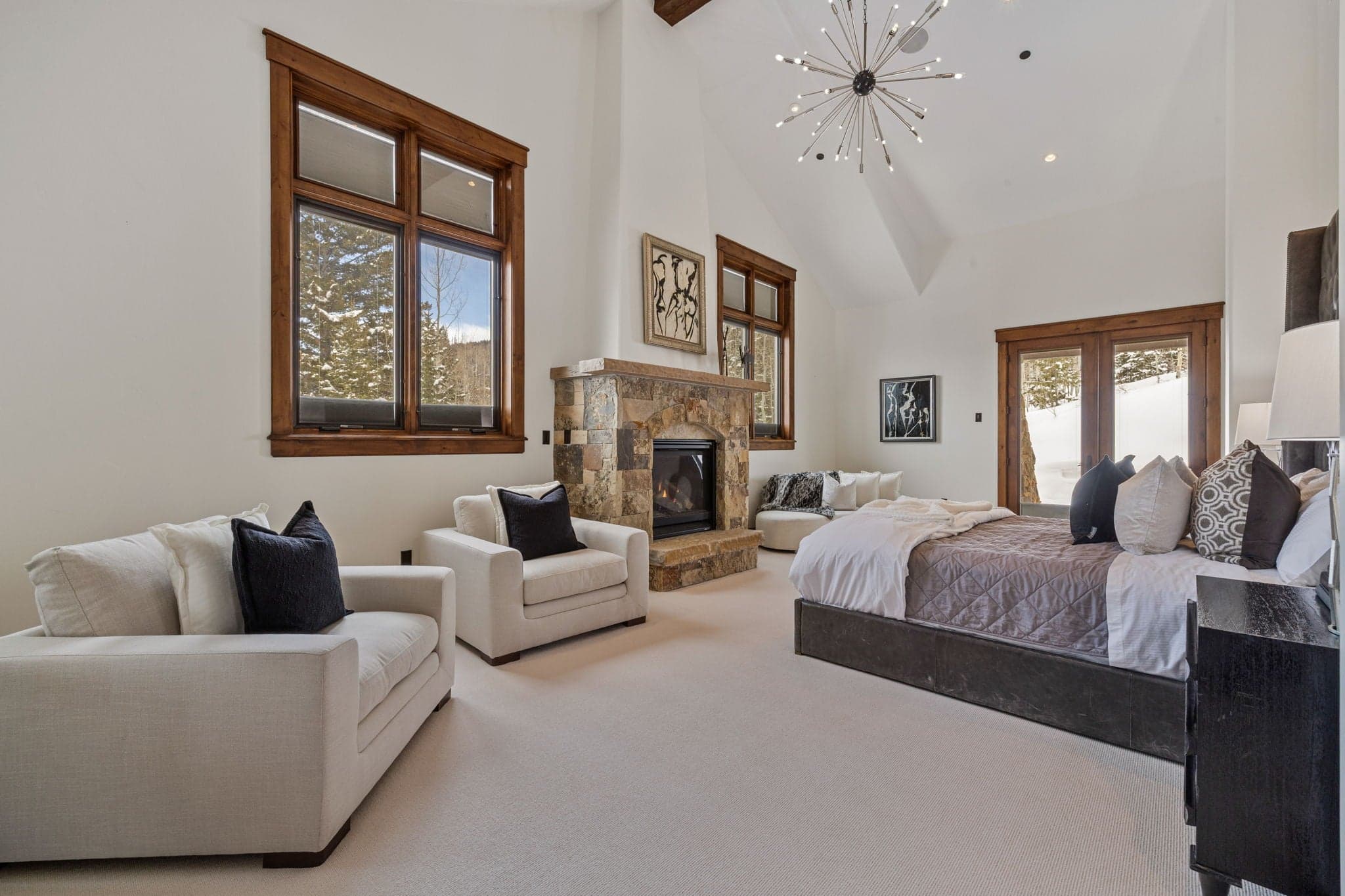 the primary master suite with king bed and lounge chairs and a stone fireplace